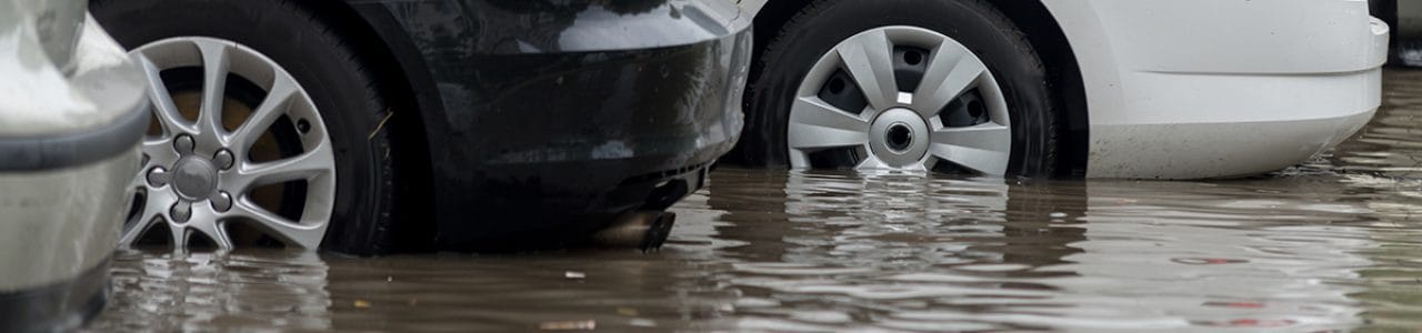 A cropped photograph showing car tyres half covered by flood water
