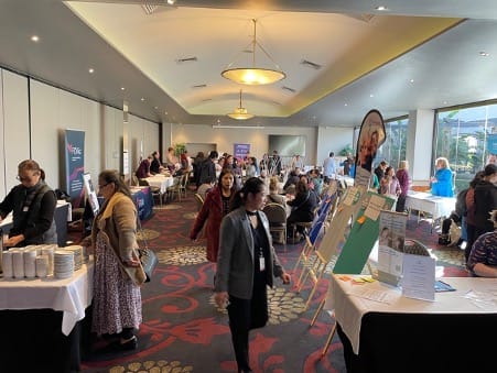 A photograph showing people at the Carers Information Session, walking between information stalls and chatting with stallholders