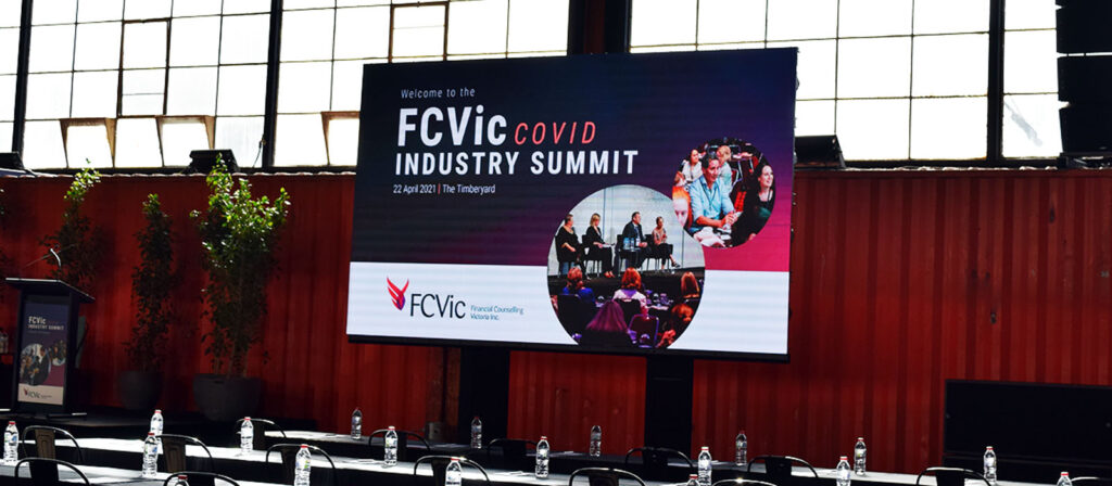 Image shows COVID Summit screen on stage at event