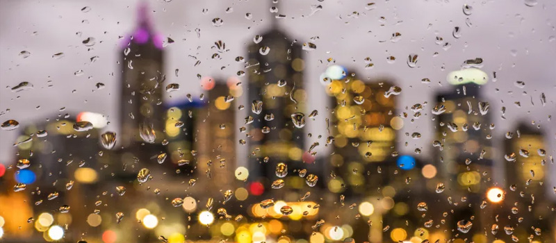Image shows a blurred Melbourne CBD behind a rainy window