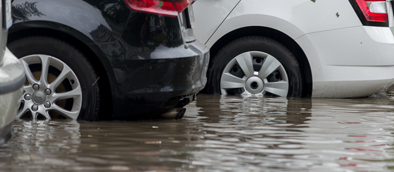 A photograph showing three parked cars with flood water halfway up their tyres