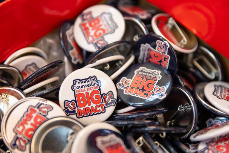 A bowl of Small Sector, Big Impact campaign badges in navy and white.
