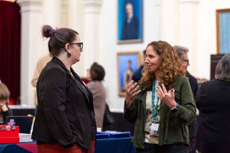 Two attendees in conversation near the EACH exhibition booth.