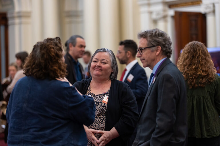 A small group chats among the exhibition booths in Queens Hall.