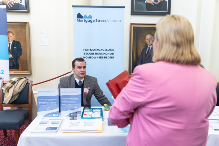 A representative from Mortgage Stress Victoria speaks with a visitor at their exhibition booth.