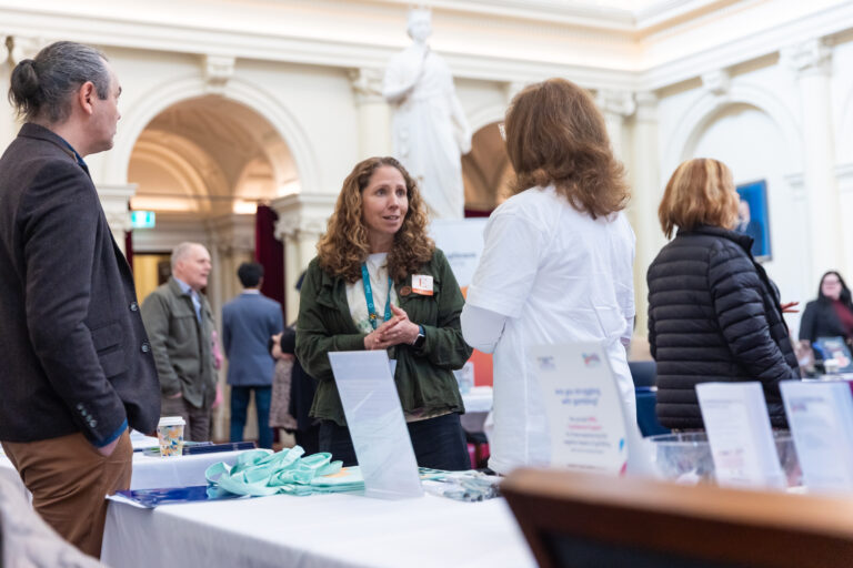 A small group in conversation near a gambling support banner and exhibition tables.