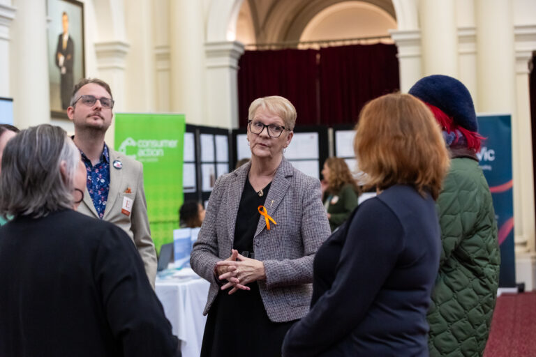 Maree Edwards MP speaks with attendees near the Consumer Action Law Centre booth.