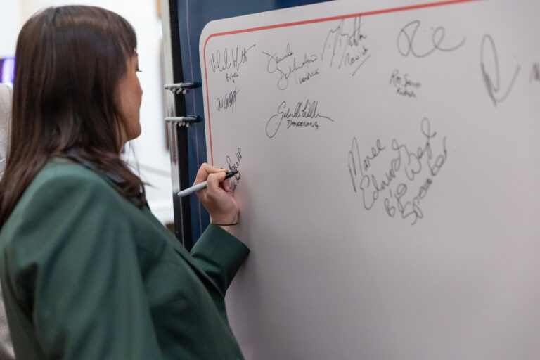 Close-up of Rachel Payne MP signing the pledge wall.