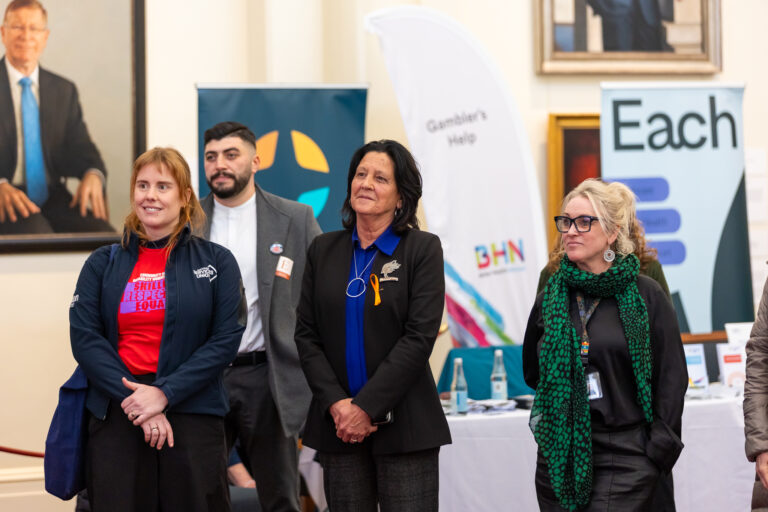 Chris Couzens MP stands with three others near the Gambler's Help and EACH exhibition banners.