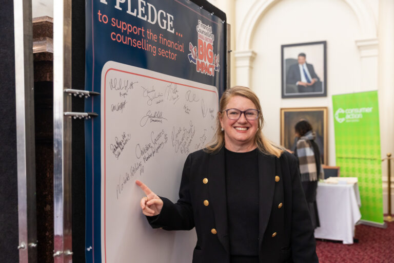 Natalie Hutchins MP points to her signature on the pledge wall in Queens Hall.
