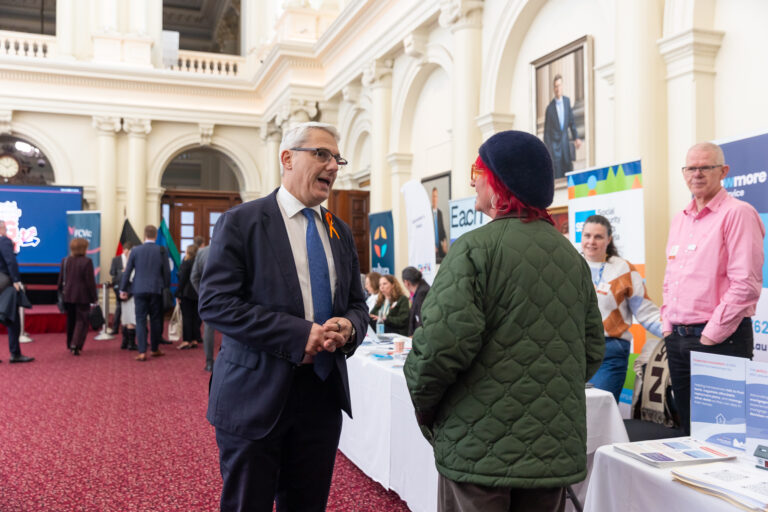 The Hon. Danny Pearson speaks with an attendee near the EACH and Social Security Rights Victoria booths.