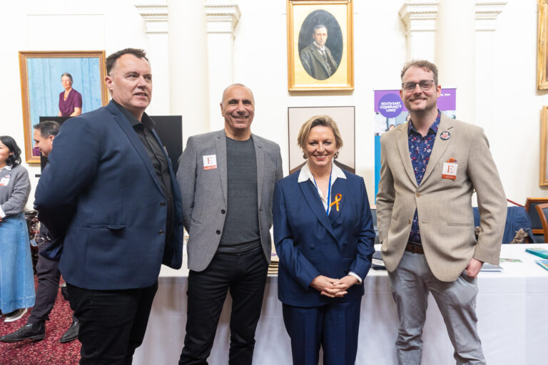 Pauline Richards MP stands with three others near exhibition booths.