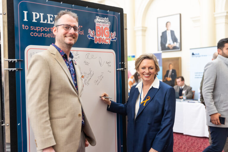 Pauline Richards MP signs the pledge wall as an FCVic representative looks on.