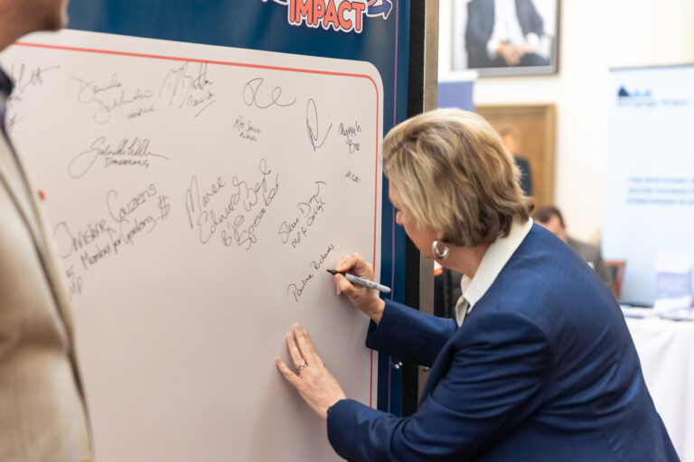 Close-up of Pauline Richards MP signing the pledge wall.