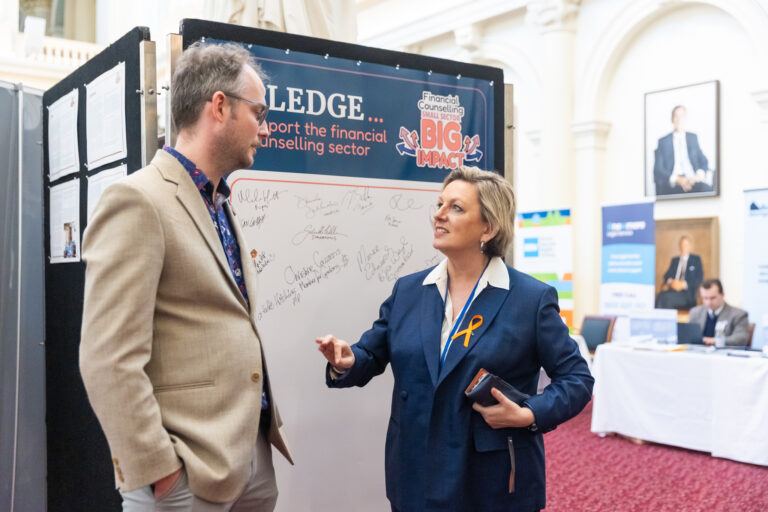 Pauline Richards MP speaks with the FCVic CEO in front of the pledge wall.