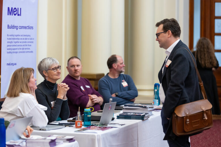 A visitor speaks with representatives at the MELI exhibition booth.
