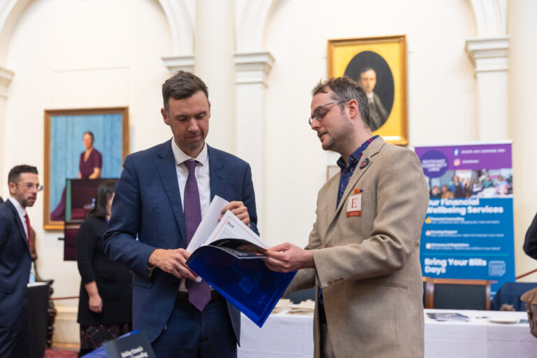 Tom McIntosh MP reviews a case study booklet with FCVic's CEO.