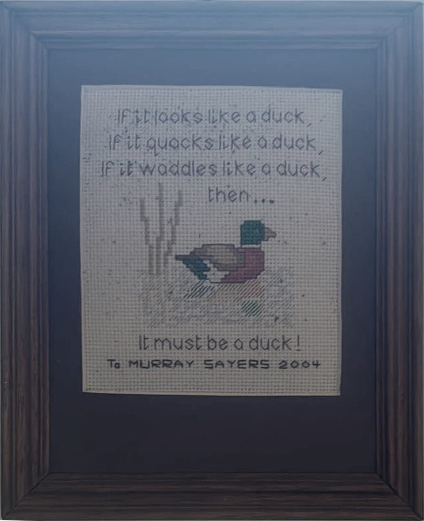 A cross stitch of the saying "If it looks like a duck, if it quacks like a duck, if it waddles like a duck then… it must be a duck" and "Murray Sayers 2004" underneath
