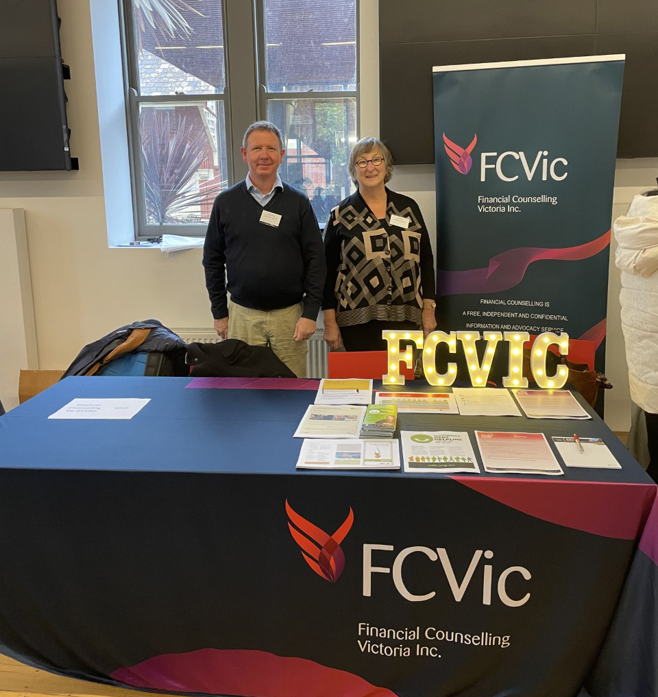 A photograph shows Sandy Ross and Julie Watson standing behind a table with the FCVic logo on it, and FCVic printed materials on top to distribute. 