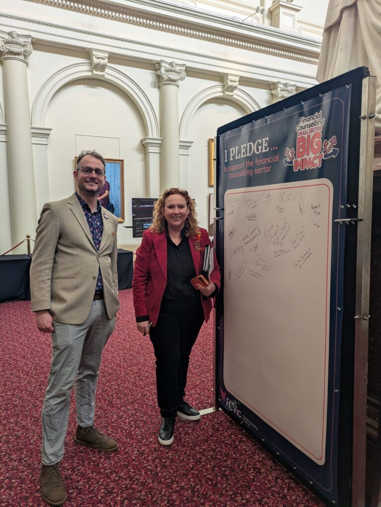 The Hon. Melissa Horne stands beside the completed "I Pledge" board with an attendee in Queen's Hall.