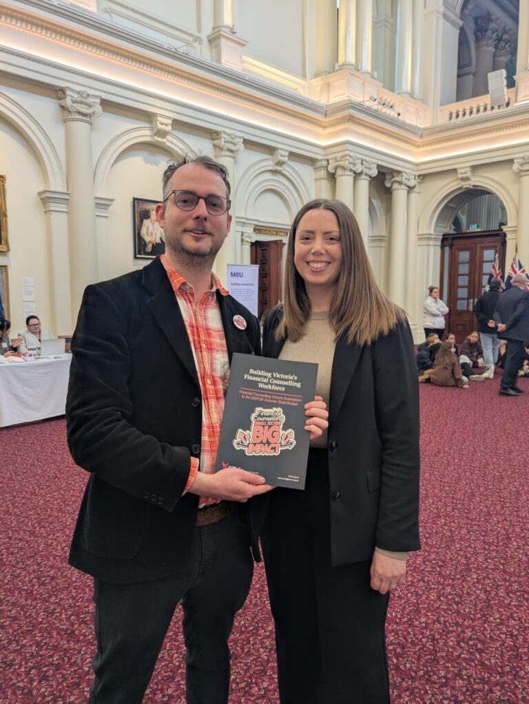 Martha Haylett MP stands with FCVic's CEO holding a copy of "Building Victoria's Financial Counselling Workforce" in Queen's Hall.