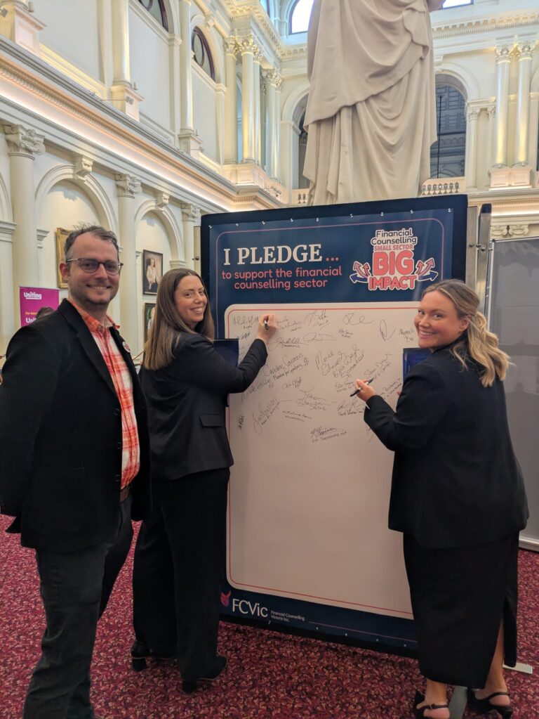 Martha Haylett MP and Ella George MP sign the "I Pledge" board alongside FCVic CEO Zyl Hovenga-Wauchope in Queen's Hall.