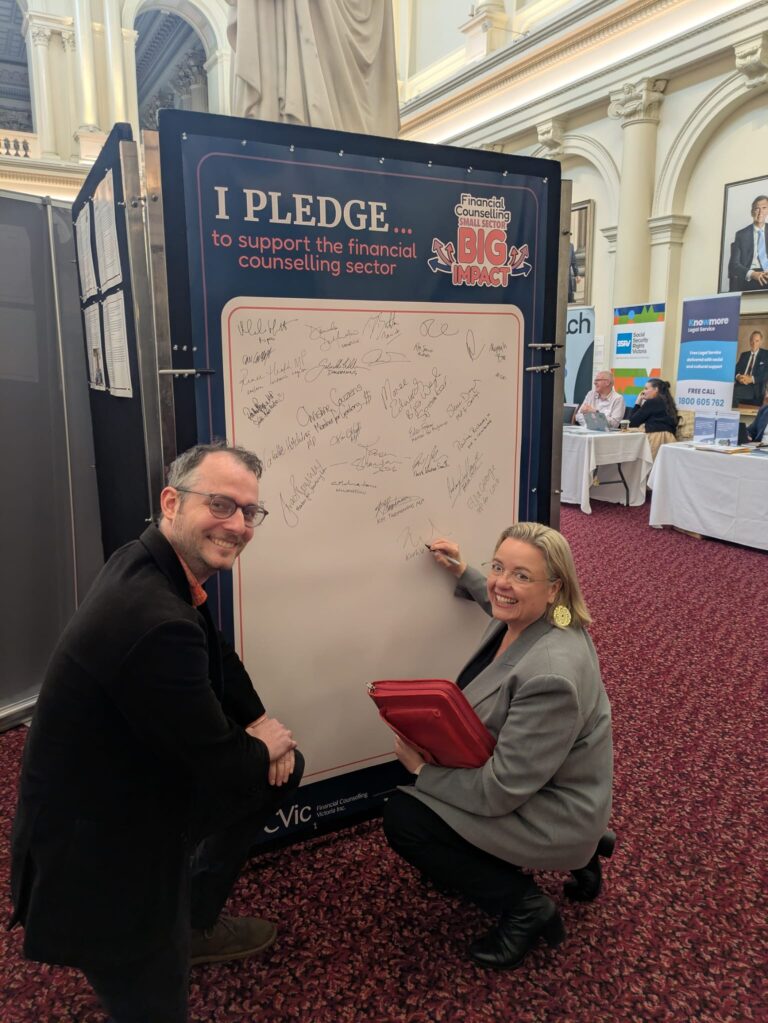 Kathleen Matthews-Ward MP signs the "I Pledge" board while an attendee looks on in Queen's Hall.