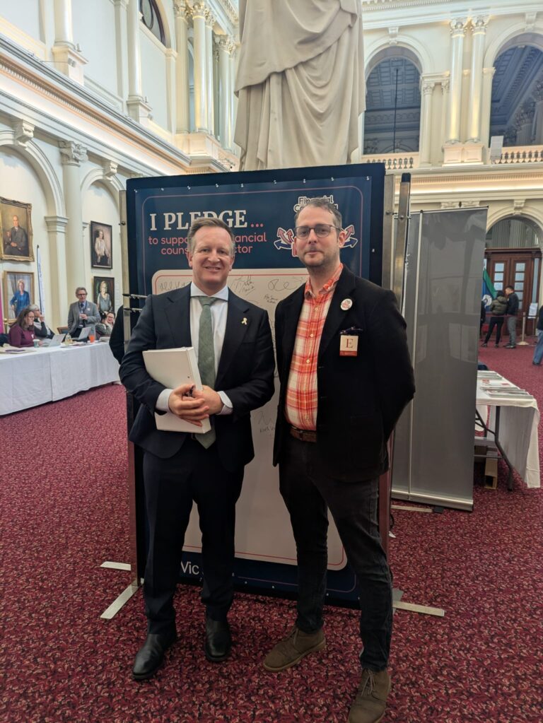 The Hon. Paul Edbrooke stands with FCVic's CEO at the "I Pledge" board in Queen's Hall.
