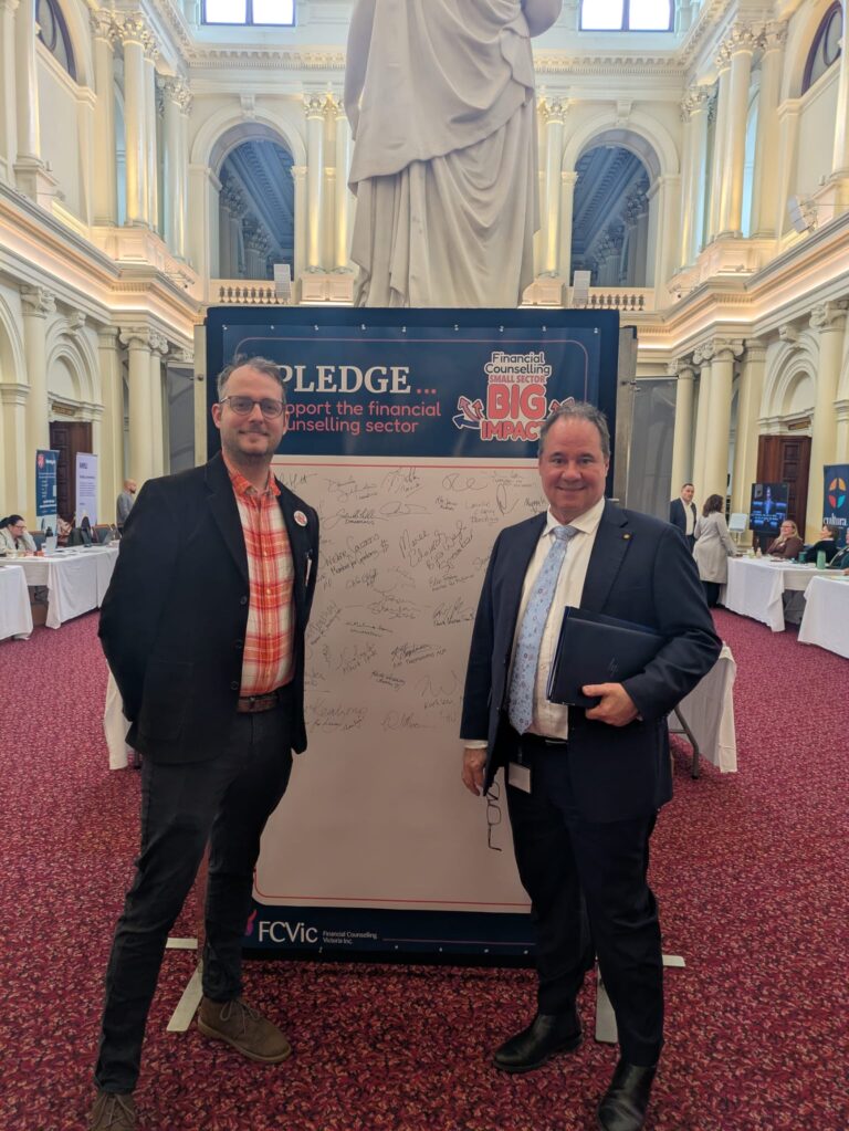 FCVic's CEO stands with Paul Mercurio MP at the "I Pledge" board in Queen's Hall.