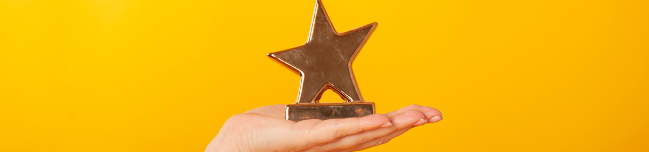a hand holding a gold star award
