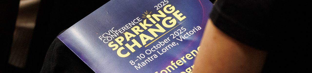 An audience member hold the 2025 FCVic Conference program