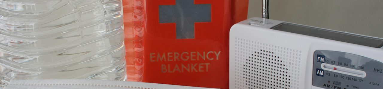A cropped image of water, emergency blankets, masks and a radio